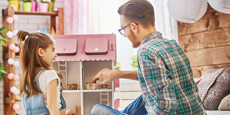 girl and dad playing with dolls house