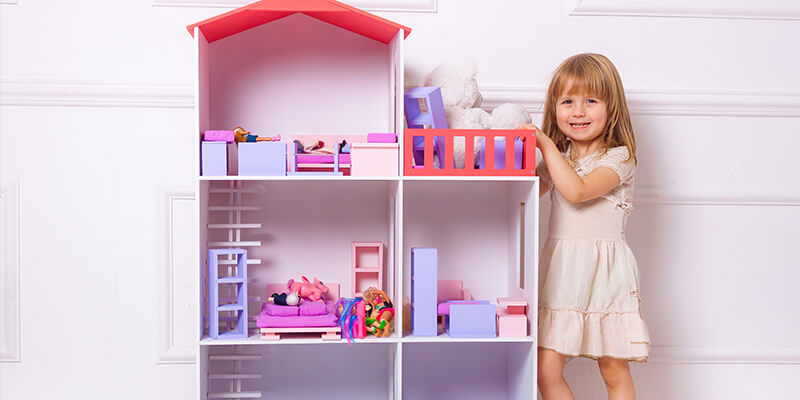 young girl playing with dollhouse